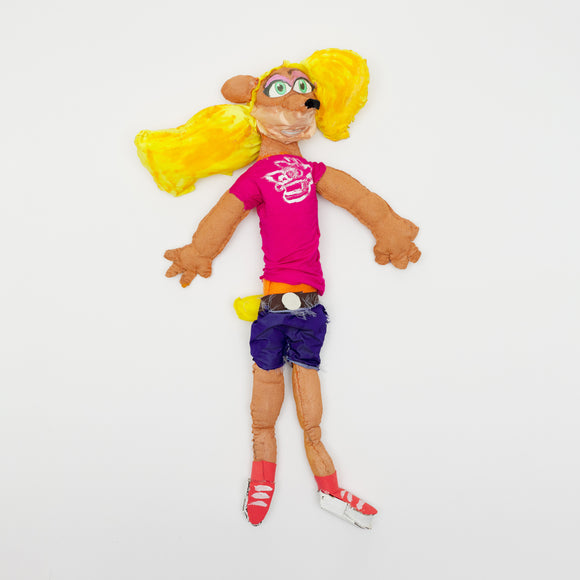 ‘A Tawna Bandicoot Plushie’ measures 28 by 18 by 7in. Composed of satin, flannel, jersey and cotton fabrics, polyfil and paper, this doll is a representation of the feminine anthropomorphic bandicoot who was created for the series as the girlfriend of Crash Bandicoot. Tawna is wearing red tennis shoes, blue shorts, a magenta t-shirt and has long blonde hair.