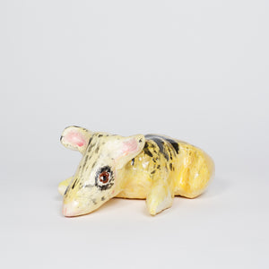 ‘Eastern Barred Bandicoot 1’ is a glazed ceramic piece of an animal by the same name. It is yellow in color and has accents of a dark brown that make up non linear shapes on its body. The ceramic piece measures 4 by 9 by 7in in size. 