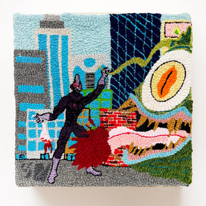 This textile artwork depicts a surreal urban battle between a monstrous figure with a glaring, reptilian eye and a humanoid character, set against a backdrop of abstracted city buildings. The textured, woven medium adds depth and tactility to the scene, blending elements of fantasy and horror with a playful, handcrafted aesthetic.