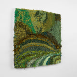 This is a twenty-three-inch square, punch-rug textile made by hand using a variety of textured yarn in various shades of green, ranging from dark olive and forest to light sea foam and teal. The different shades form patches and stripes, the highly textured work is mounted on stretcher bars and hung on the wall.