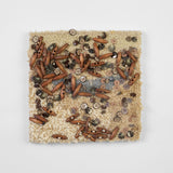 This is a sixteen-inch square, punch-rug textile made by hand using tan, beige, and grey cotton yarn. The surface of the highly textured work is intuitively adorned with dozens of smooth, beige buttons and oblong, wooden beads affixed with tan thread. It is mounted on stretcher bars and hung on the wall.