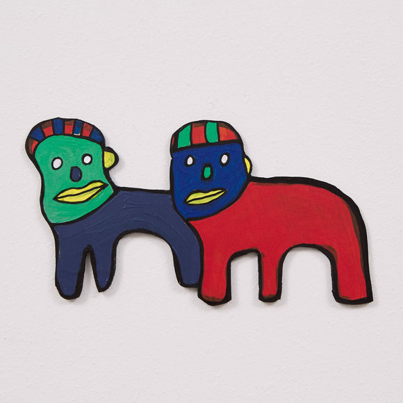 This 6 by 11 by 1/4th-inch wood sculpture by Hugo Rocha depicts two creatures with a vivid color palette. The figures are distinct but cut out of one piece of wood. The left head is green with a yellow ear and nose, and the right head is blue with similar features. Both heads have striped features resembling hair. The left’s body is navy blue, and the right body is bright red, both outlined in black.