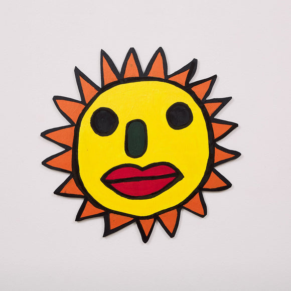 This 20 by 20 by 1/4th-inch wood sculpture by Hugo Rocha depicts a stylized sun with a human face. The sun's round, yellow face features bold, black eyes, a green nose, and red lips, giving it a playful and expressive character. The sun's rays are represented with orange pointed triangles that surround the face. The piece is outlined in black, emphasizing its vibrant colors and whimsical design.