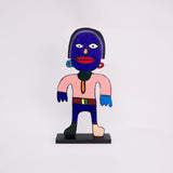 This 37 by 18 by ½-inch wood sculpture by Hugo Rocha portrays a stylized human figure standing upright on a black base. The figure's face is painted blue with wide white eyes and a large red mouth. The body is mostly pink with one hand dark blue and the other light blue. The figure wears a belt with a yellow and green buckle. One foot is dark green, the other beige. The figure has prominent earrings, and a distinct, colorful, abstract appearance, outlined in black for emphasis.