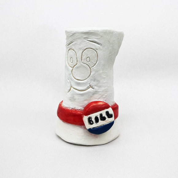 This ceramic sculpture depicts a playful, cartoonish representation of a bill or rolled document, complete with a smiling face and a “BILL” button in red, white, and blue. The simple lines and patriotic color scheme evoke nostalgia for educational cartoons, blending humor with a familiar symbol of legislative process.