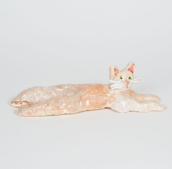 This ceramic sculpture depicts a relaxed, elongated cat with a serene expression, crafted in soft tones of cream and light peach. The figure’s stretched body and gentle glaze create a sense of calm and simplicity, emphasizing the cat's peaceful demeanor.