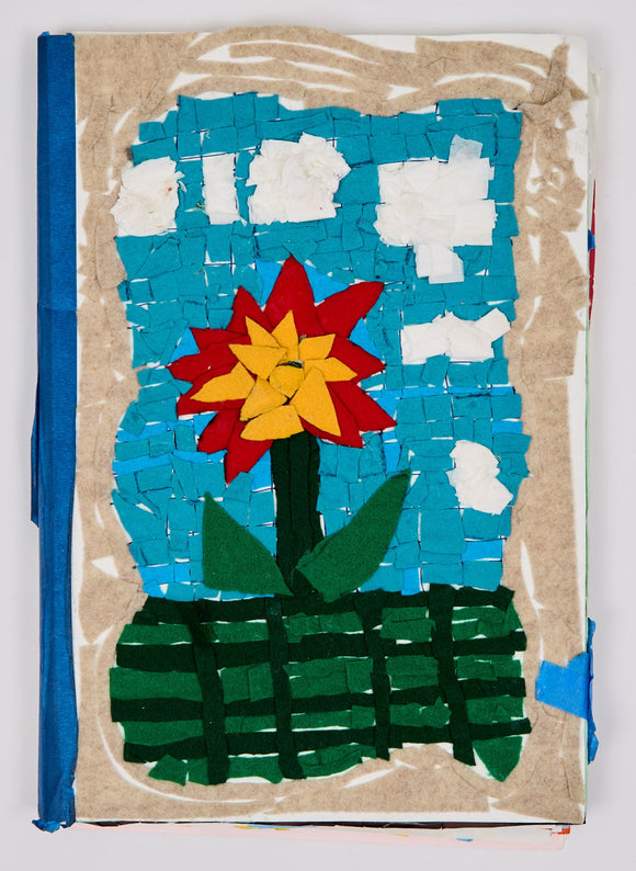 A bold flower with layered yellow and red petals stands against a sky of textured blue squares and cotton clouds, framed in tan and set above a deep green woven base.