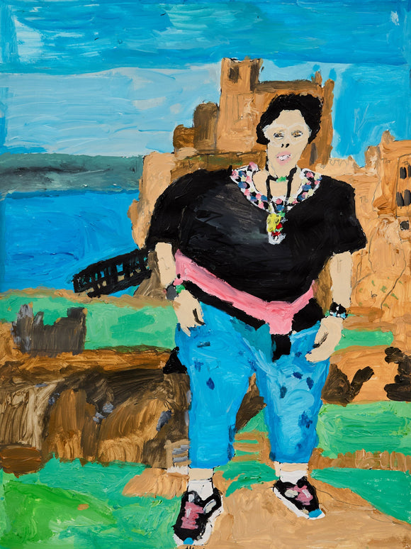 A woman with bold jewelry and a pink sash poses confidently before ancient sandstone ruins, the deep blue of water and sky adding drama to the sunlit scene.