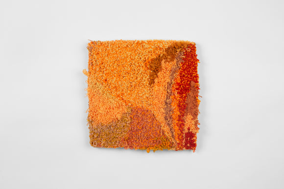 This is a fifteen inch square, punch-rug textile made by hand using a variety of textured cotton yarn in various shades of orange, ranging from pastel to darker, muted oranges with some fiery red. Threads overhang the borders of the work, it is mounted on stretcher bars and hung on the wall.