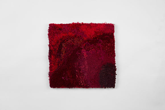 This is a twenty-one-inch square, punch-rug textile made by hand using a variety of textured yarn in colors that include dark burgundy, fiery red, and deep fuchsia. Loops and threads dangle from the work’s textured surface, it is mounted on stretcher bars and hung on the wall.