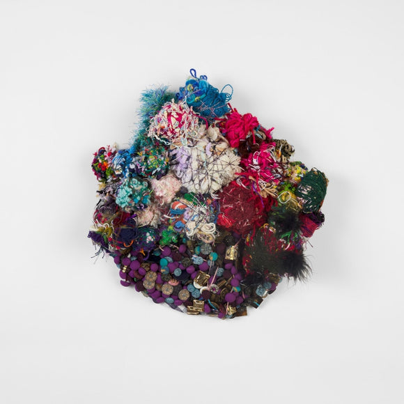 This round, mixed media work consists of sewn buttons, beads, and several spherical weavings of yarn in a range of cool blue and forest green to dark red and hot pink. 