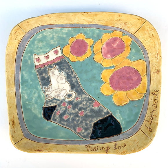 Hand made glazed ceramic tile with an illustration of a sock with a three cats on it. Three flowers with a yellow petals and red buds are on the right hand side of the sock.